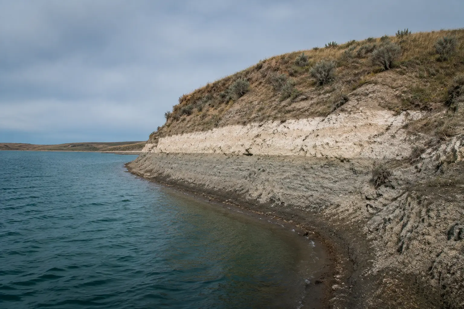 Lake Diefenbaker shoreline with a pale former high-water band above the current damp edge